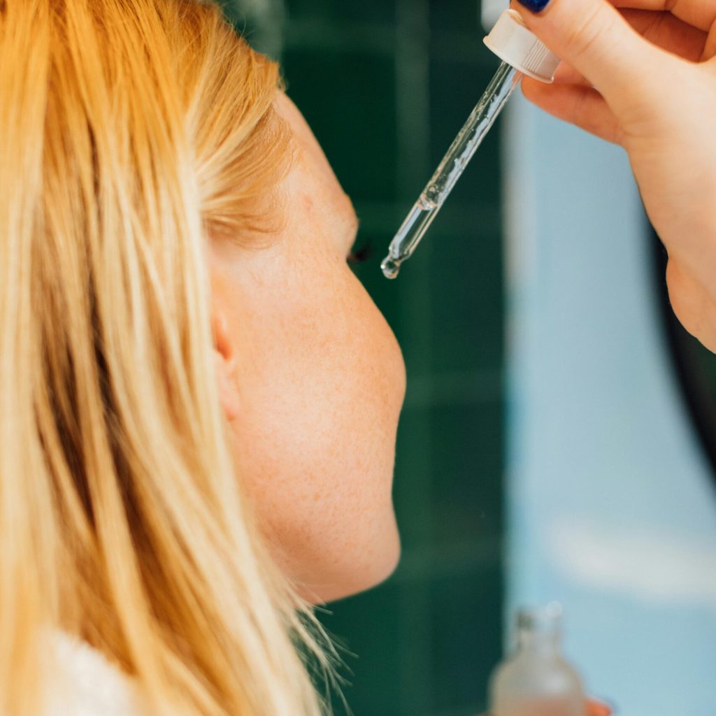 Close-up of a woman applying skincare serum with a dropper for self-care routine.